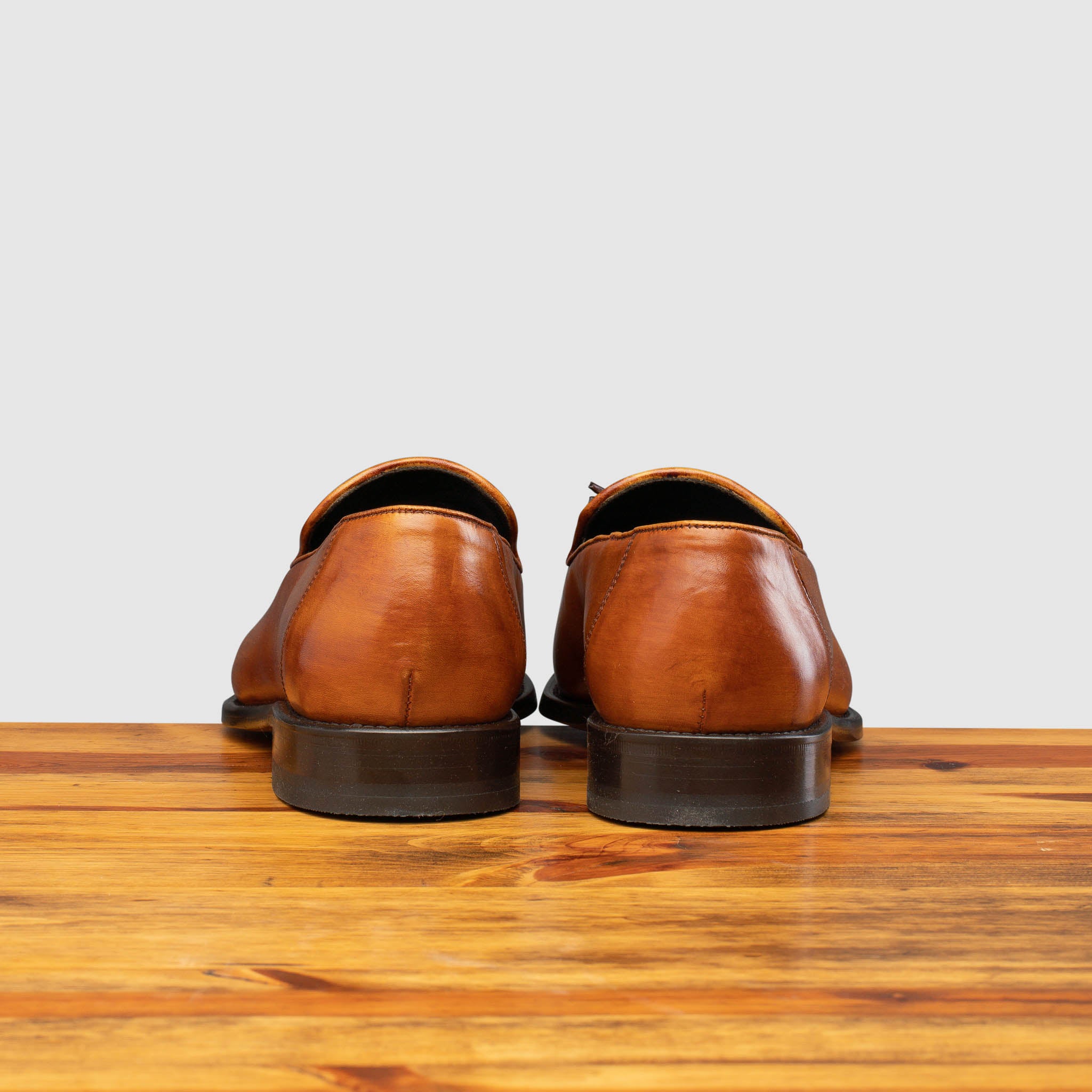 Back profile of Z993 Calzoleria Toscana Dark Caramel David Tassel Slip-On on top of a wooden table